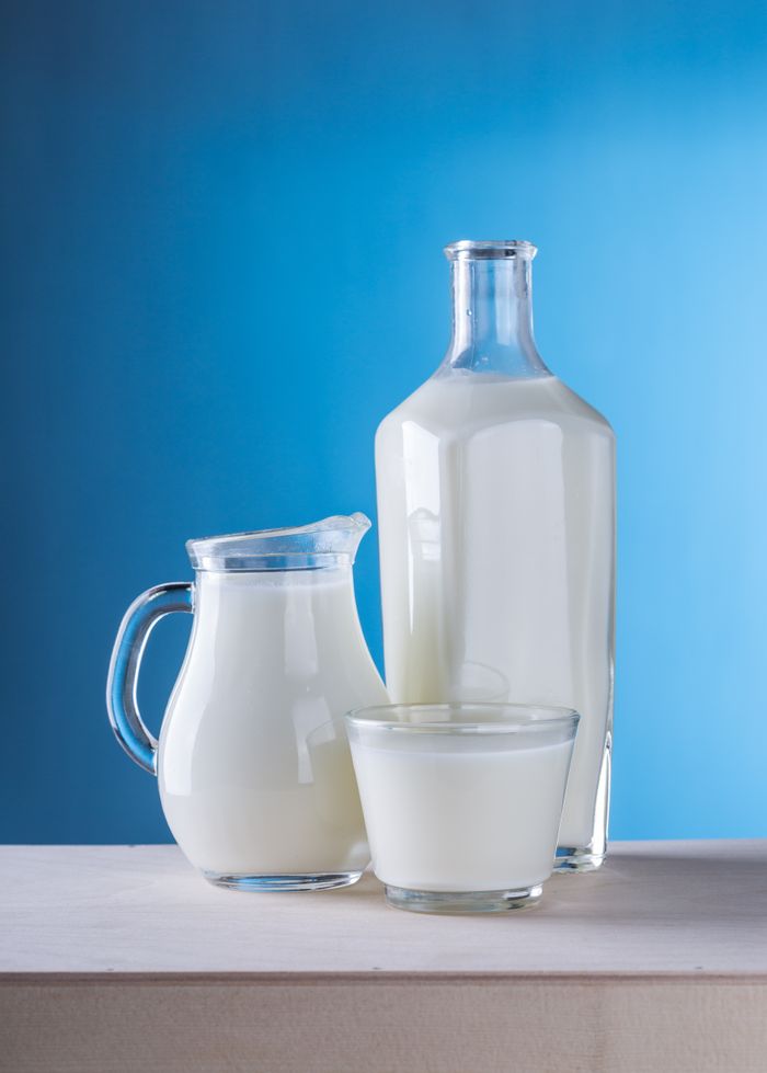 Home Minimalist still life of fresh milk in glassware against a blue background.