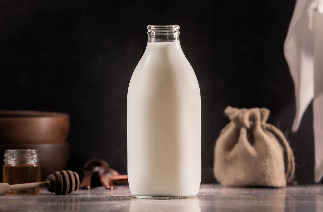 Home Aesthetic glass milk bottle with rustic kitchen elements in soft lighting.