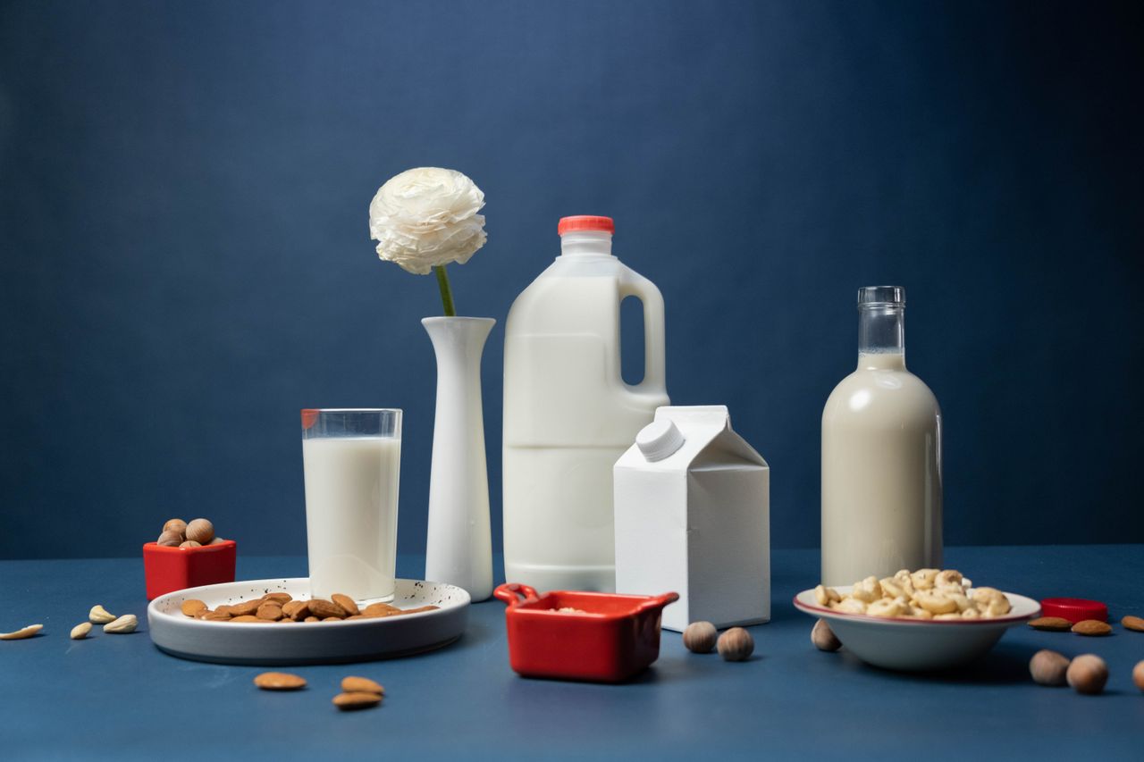 Home Still life of assorted vegan nut milks with nuts and decorative flower in studio.